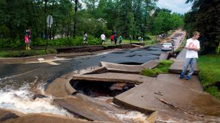 Duluth street with buckled and destroyed pavement, water flowing