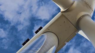 A photo of a wind turbine with blue sky and clouds.