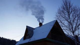 House in winter with snow on the roof and smoke coming from its chimney