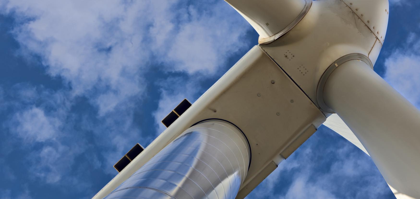 A photo of a wind turbine with blue sky and clouds.