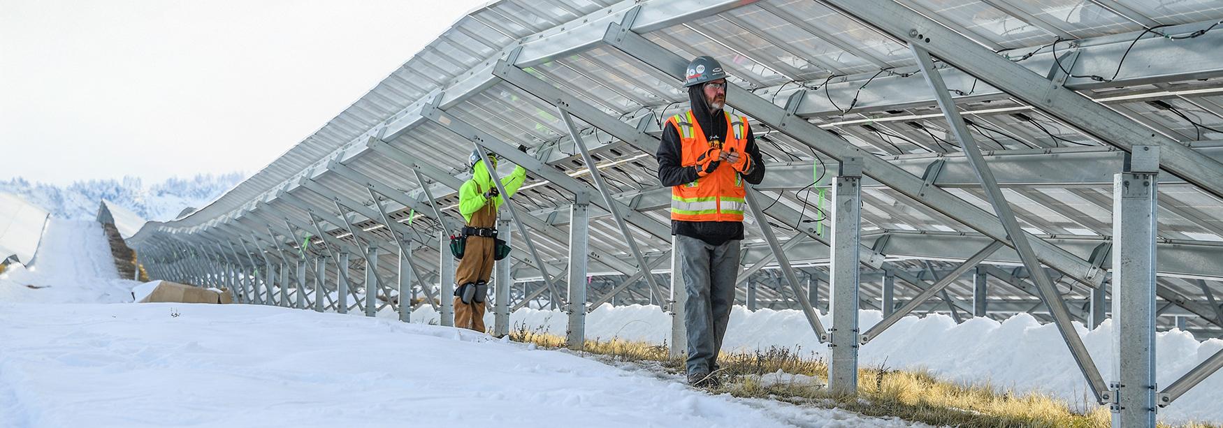 Workers inspecting a solar farm in the snow