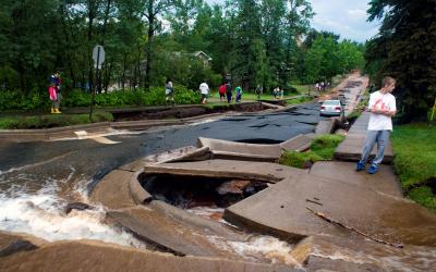 Duluth street with buckled and destroyed pavement, water flowing